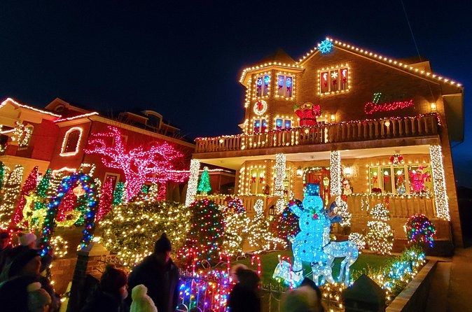 A Brooklyn house and garden covered in Christmas lights, figures glowing on the lawn