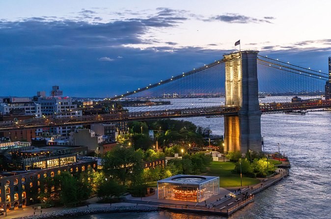 A Brooklyn waterfront park, its carousel pavilion and the bridge above it at dusk