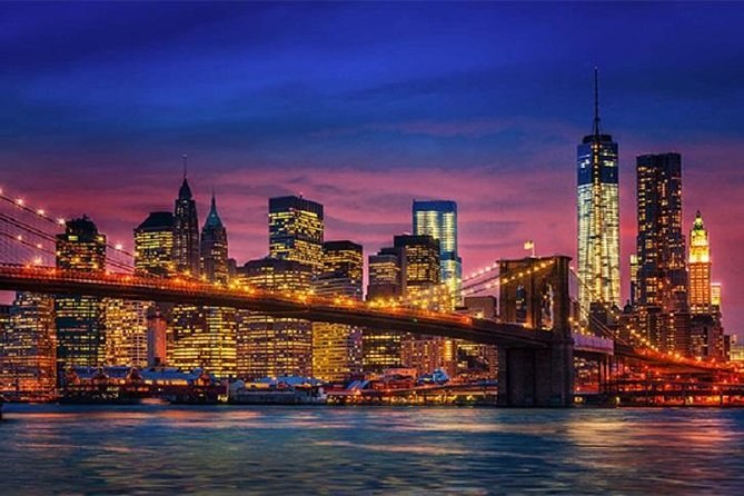 Lower Manhattan's towers and a lit suspension bridge under a violet twilight sky