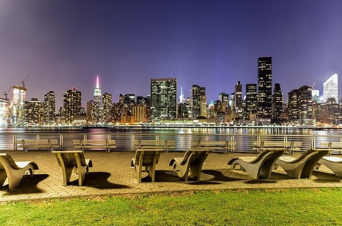 The Midtown skyline across the East River at dusk, from a waterfront park in Queens