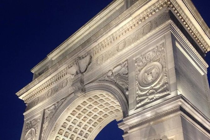 The marble arch in Washington Square Park lit white against the night sky